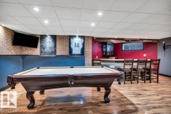 Finished space featuring wood-finish flooring, a built-in bar with seating, brick-patterned wall accents, and recessed ceiling lighting - 