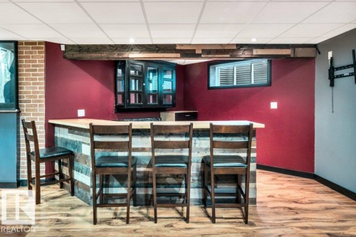 Custom bar area featuring a wood-finish countertop, paneled front, and built-in cabinetry - 1107 Chahley Crest, Edmonton, AB 