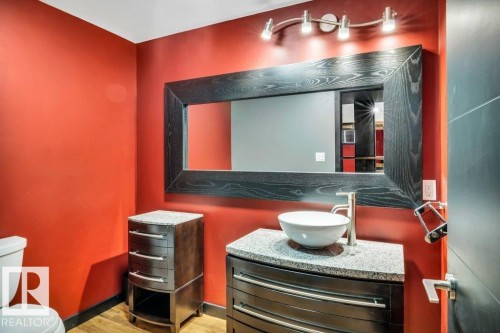 Powder room featuring a vessel sink, single-handle faucet, granite countertop, dark wood-finish vanity, and a large framed mirror with track lighting - 1107 Chahley Crest, Edmonton, AB 