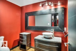 Powder room featuring a vessel sink, single-handle faucet, granite countertop, dark wood-finish vanity, and a large framed mirror with track lighting - 