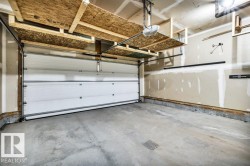 Spacious garage featuring a concrete floor, overhead shelving, automatic garage door opener, and interior wall storage systems - 