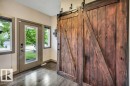 Dark-stained wood-finish flooring complements the modern barn door on a black metal track - 1107 Chahley Crest, Edmonton, AB 