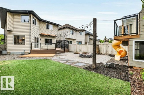 Expansive backyard featuring a manicured lawn, paver patio, and stone fire pit - 1107 Chahley Crest, Edmonton, AB 