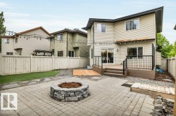 Paver patio featuring a stone fire pit, wood-finish decking, and low-maintenance landscaping - 