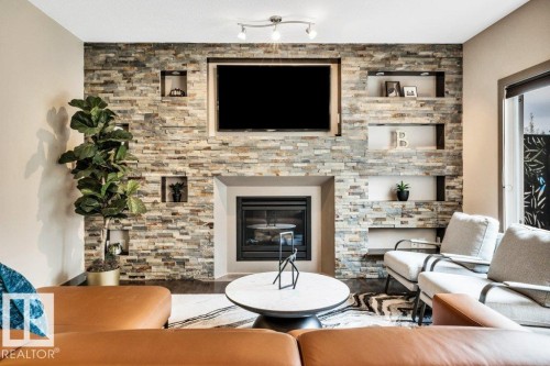 Stacked stone feature wall with integrated gas fireplace, recessed display niches, and an embedded television mount - 1107 Chahley Crest, Edmonton, AB 