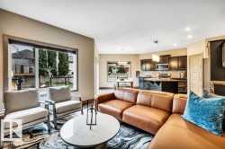 Open-concept living space featuring expansive windows, recessed lighting, wood-finish cabinetry, stainless steel appliances, and a kitchen island with seating - 