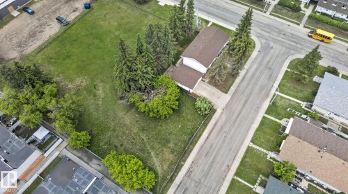 Expansive corner lot featuring a detached residence with an attached garage, mature evergreen trees, and a substantial grassed area - 13908 64 Street, Edmonton, AB 