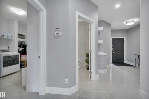 Spacious entry hallway with light gray walls, white trim, and glossy tile flooring - 3898 Robins Crescent, Edmonton, AB 