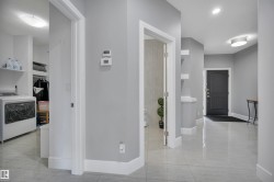 Spacious entry hallway with light gray walls, white trim, and glossy tile flooring - 