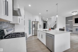 Modern kitchen featuring a gas range with stainless steel hood, mosaic tile backsplash, and white cabinetry - 