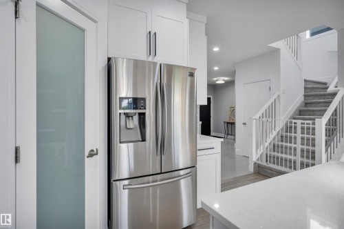 Stainless steel refrigerator with ice and water dispenser, framed by white cabinetry - 3898 Robins Crescent, Edmonton, AB 
