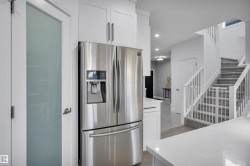 Stainless steel refrigerator with ice and water dispenser, framed by white cabinetry - 