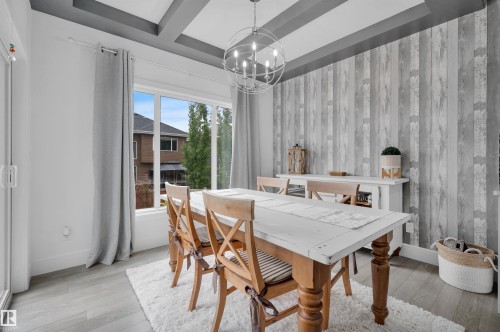 Dining area featuring a wood-finish accent wall, coffered ceiling, and large window - 3898 Robins Crescent, Edmonton, AB 