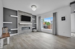 Contemporary living space featuring a tiled fireplace with an integrated electric insert, a mounted television, and floating shelving - 