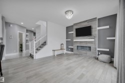 Living area featuring wood-finish flooring, a contemporary tiled fireplace surround with an integrated electric fireplace, and a crystal flush mount ceiling fixture - 