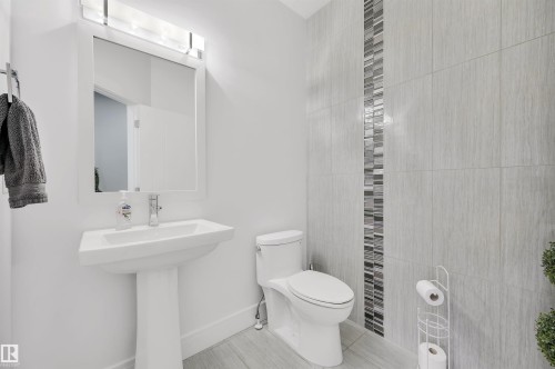 Pedestal sink with a framed mirror and overhead lighting fixture - 3898 Robins Crescent, Edmonton, AB 
