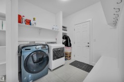 Dedicated laundry area featuring tile flooring, built-in shelving, and a wall-mounted coat rack - 