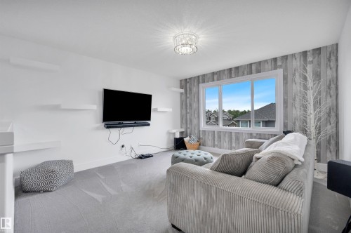 Living area featuring a textured accent wall, a window with exterior views, and neutral color palette - 3898 Robins Crescent, Edmonton, AB 