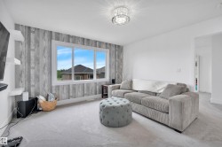 Spacious room featuring light grey carpeting, a large window with white trim, and a decorative accent wall with a wood-look finish - 