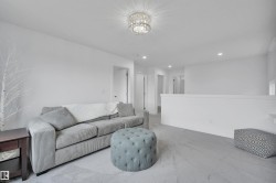 Carpeted room featuring a ceiling-mounted crystal chandelier, recessed lighting, and a white half-wall - 