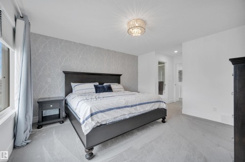 Carpeted bedroom featuring a patterned accent wall and a window with roller blinds - 3898 Robins Crescent, Edmonton, AB 