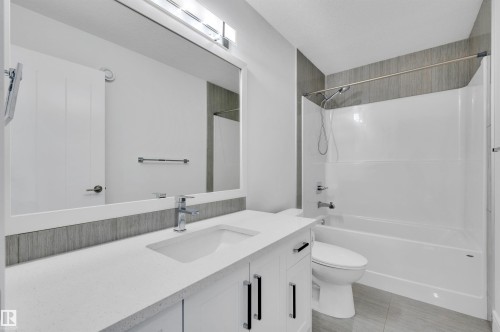 Bathroom featuring a vanity with a white countertop and integrated sink, chrome faucet, and white cabinetry with dark pulls - 3898 Robins Crescent, Edmonton, AB 
