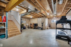 Spacious unfinished basement featuring exposed wood joists and concrete flooring - 