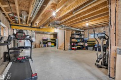 Unfinished lower level featuring exposed wood joists and concrete flooring - 