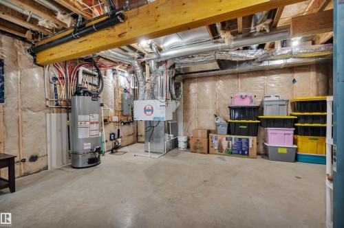 Unfinished basement featuring exposed wooden beams, concrete flooring, a water heater, and visible HVAC ductwork - 3898 Robins Crescent, Edmonton, AB 