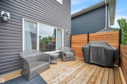 Outdoor wooden deck with horizontal slatted privacy fencing, dark gray horizontal siding, and a large sliding glass door - 