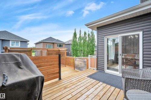 Expansive wood deck with horizontal slat privacy screen, white railing, and sliding glass door access to the interior - 3898 Robins Crescent, Edmonton, AB 