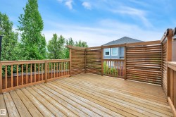 Spacious wood-finish deck featuring slatted privacy screens and coordinating wood railings - 