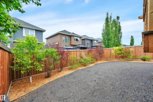 Gravel-surfaced backyard featuring new wood fencing and a landscaped perimeter with mulch and young trees - 3898 Robins Crescent, Edmonton, AB 
