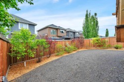 Gravel-surfaced backyard featuring new wood fencing and a landscaped perimeter with mulch and young trees - 