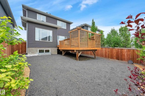 Rear exterior featuring dark gray siding, a wood deck with privacy screening, and a gravel ground cover - 3898 Robins Crescent, Edmonton, AB 
