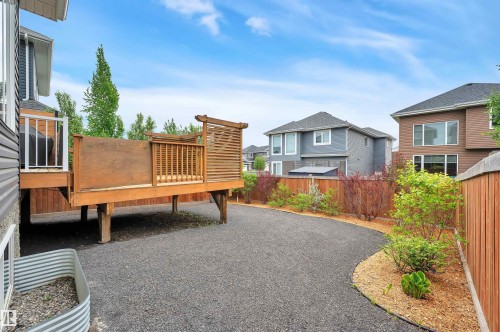 Elevated wood deck with privacy screen, gravel patio area, landscaped garden beds, and wood fencing - 3898 Robins Crescent, Edmonton, AB 
