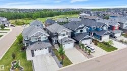 Residential streetscape featuring a collection of modern homes with landscaped front yards and paved driveways - 
