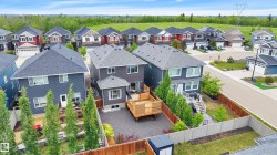 Rear exterior featuring a multi-level wood-finish deck, privacy fencing, and a manicured lawn - 