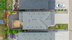 Overhead property perspective featuring a light gray shingle roof, a generously sized concrete driveway, and a wooden deck - 