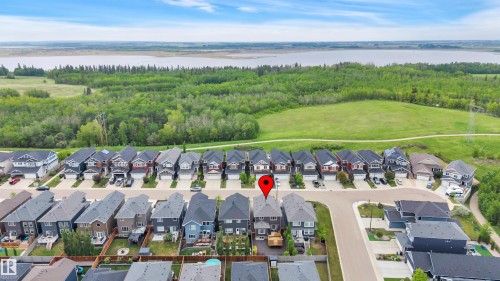 Aerial perspective highlighting the property within a residential development, bordered by expansive green spaces and a distant body of water - 3898 Robins Crescent, Edmonton, AB 