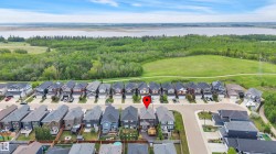 Aerial perspective highlighting the property within a residential development, bordered by expansive green spaces and a distant body of water - 