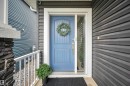 Entryway featuring a blue paneled door with sidelight, dark horizontal siding, and a stone-clad column with white railing - 3898 Robins Crescent Nw, Edmonton, AB  - Outdoor 