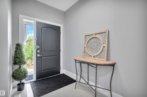 Entryway featuring a dark paneled door with a sidelight, light gray walls, white baseboards, and light-toned flooring - 3898 Robins Crescent, Edmonton, AB 