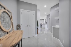 Hallway featuring light gray walls, white trim, recessed lighting, double closet doors, and light-toned tile flooring - 