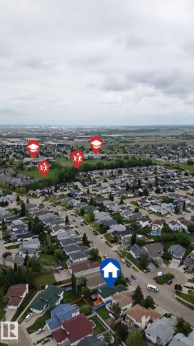 Aerial perspective of a residential neighborhood featuring numerous single-family homes with pitched roofs, surrounded by mature trees and green spaces - 3928 30 Street, Edmonton, AB 