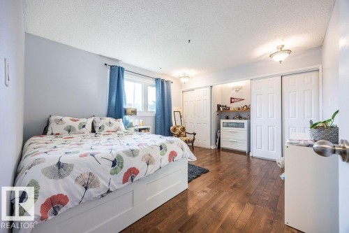 Spacious bedroom featuring wood-finish flooring, light-toned walls, and a large window with natural light - 17932 93 Avenue, Edmonton, AB 