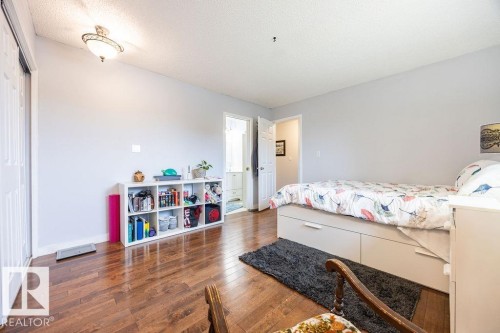 Bedroom featuring wood-finish flooring, light grey walls, and a white bi-fold closet door - 17932 93 Avenue, Edmonton, AB 