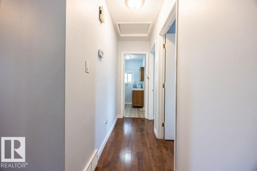 Hallway featuring wood-finish flooring, white baseboards, and light-toned walls - 17932 93 Avenue, Edmonton, AB 