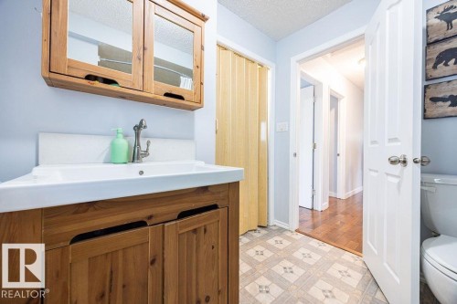Bathroom featuring a wood-finish vanity with an integrated white sink and chrome faucet - 17932 93 Avenue, Edmonton, AB 