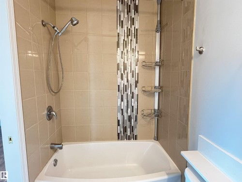 Bathtub shower combination featuring light beige ceramic wall tile and a decorative mosaic tile accent - 17932 93 Avenue, Edmonton, AB 